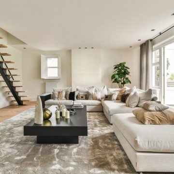 Comfortable sofa with cushions placed against light wall with TV and decorations in modern loving room